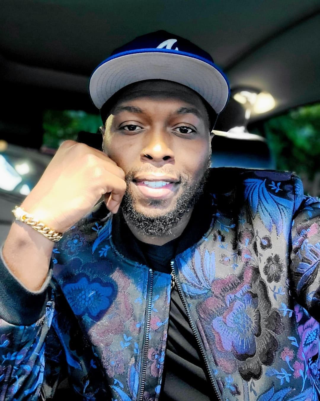 JChosen wearing a blue cap and patterned jacket, seated inside a car.